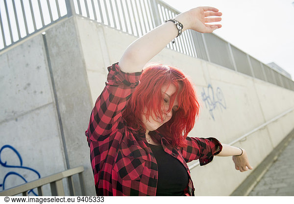 Young teenage girl dancing red dyed hair