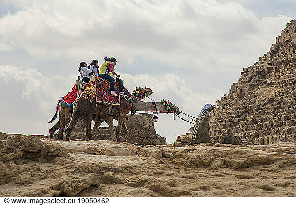 Young teenagers riding camels at the Pyramids of Giza