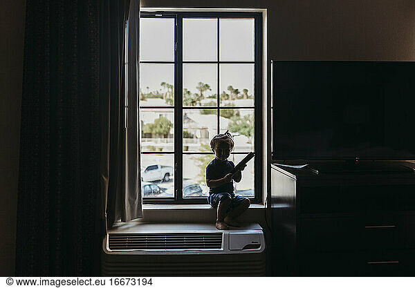 Young toddler boy sitting in window of hotel room in Palm Springs
