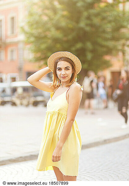 Young tourist girl in a yellow dress and a hat in the summer