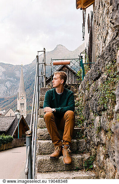 young tourist sits on the stairs in the streets of Hallstatt  Austria