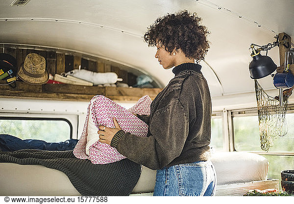 Young woman adjusting pillow on bed in motor home during camping