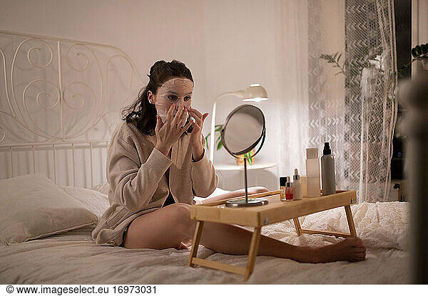 Young woman adjusting sheet mask