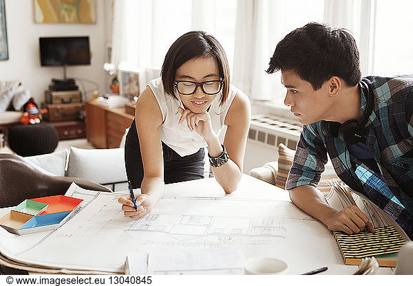 Young woman analyzing blueprint with man at home