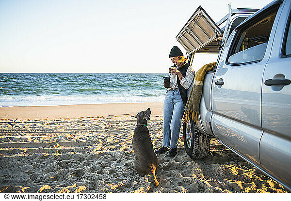 Young woman and her dog while beach car camping alone