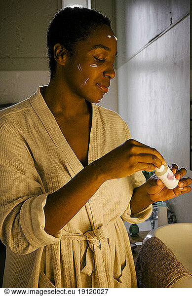 Young woman applying beauty product on face
