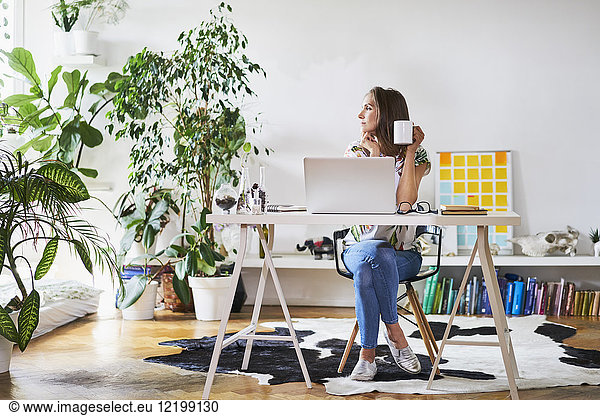 Young woman at home at desk looking sideways