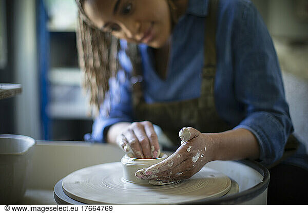 Young woman at pottery wheel in art studio