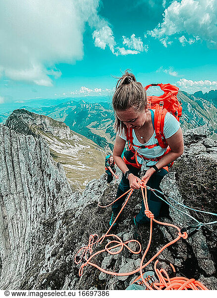 Young woman belaying climber on narrow ridge (Reitergrat) in Swiss alp