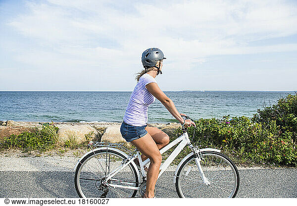 Young Woman biking by Cape Cod beaches coastal bike path