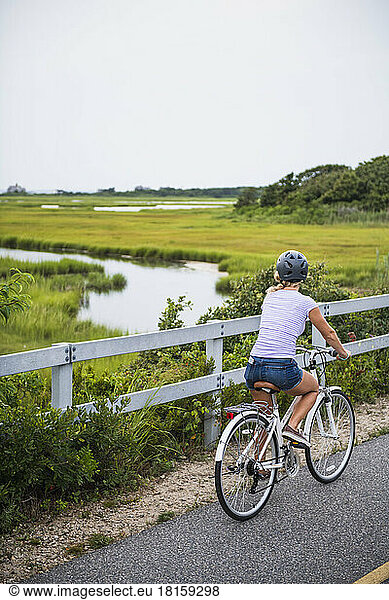 Young Woman biking through Cape Cod Marshes bike path