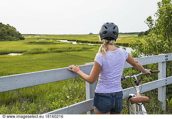 Young Woman biking through Cape Cod Marshes bike path