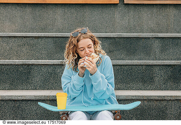 Young woman bite street food outdoors and drinking coffee.