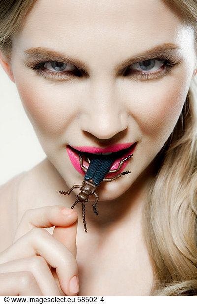 Young woman biting plastic beetle