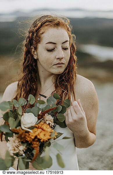 Young woman bride holding flowers in wedding dress red hair
