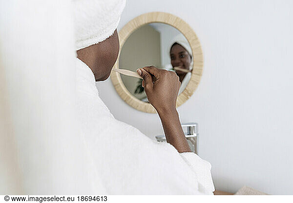 Young woman brushing teeth in bathroom at home