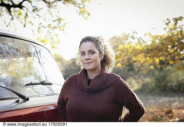 Young woman by van in autumn forest
