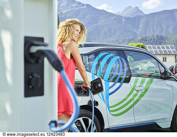 Young woman charging electric car