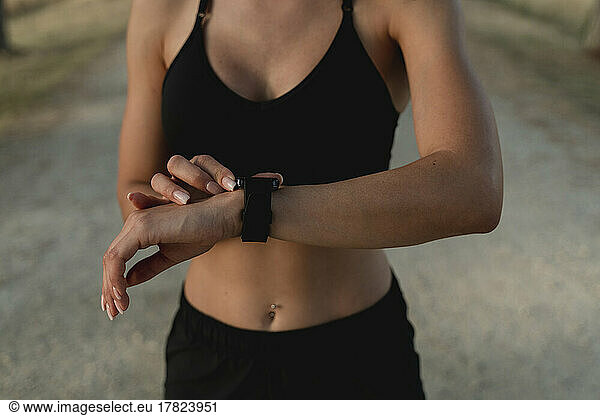 Young woman checking time in smart watch