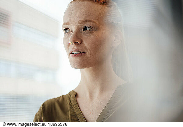 Young woman contemplating at window
