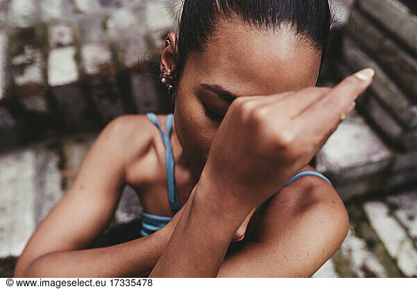 Young woman covering face with hands