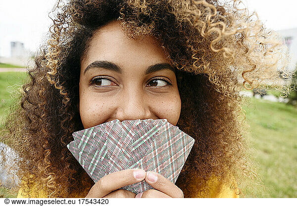 Young woman covering mouth with playing cards