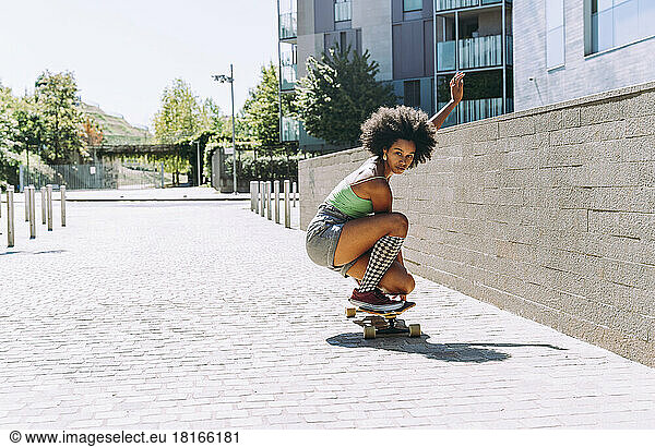 Young woman crouching on skateboard outside building