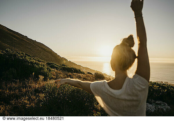Young woman dancing in front of clear sky at sunset