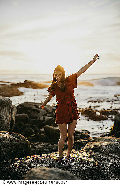 Young woman dancing on rock at beach