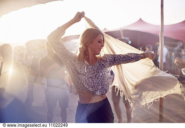 Young woman dancing with scarf at music festival