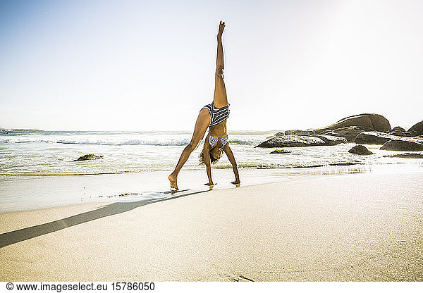 Young woman doing a cartwheel on the beach