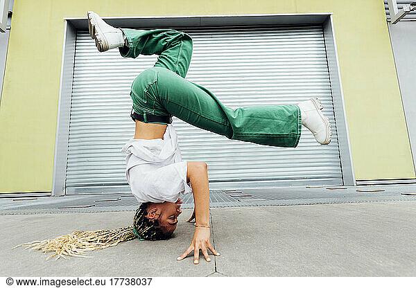 Young woman doing headstand in front of shutter