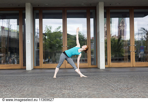 Young woman doing yoga in urban city