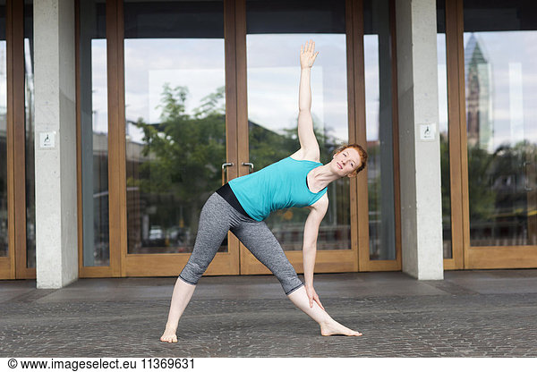 Young woman doing yoga in urban city