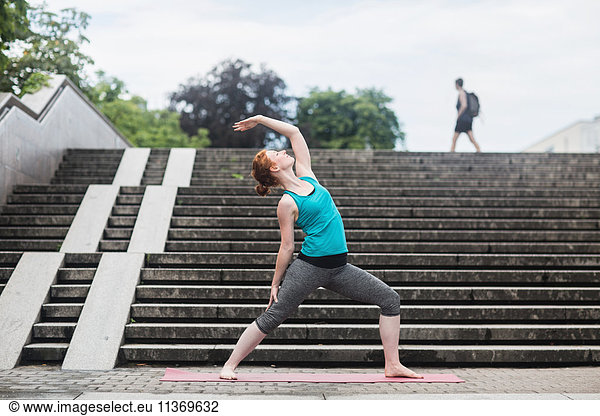 Young woman doing yoga on staircases in urban city