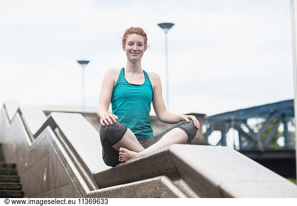 Young woman doing yoga on wall in urban city