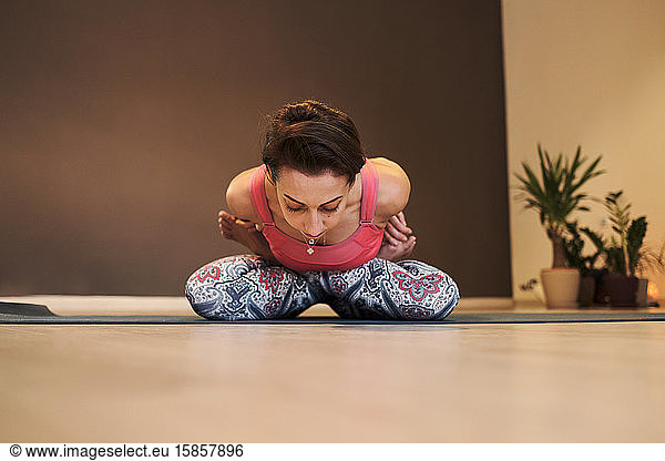 young woman doing yoga on yoga mat in atmospheric yoga studio