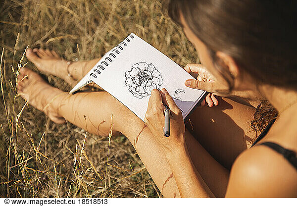 Young woman drawing flower on sketch pad