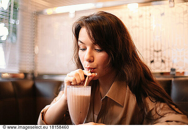 Young woman drinking chocolate milkshake in restaurant