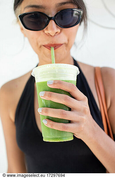 Young woman drinking green juice