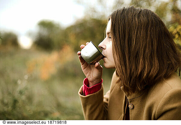 Young Woman Drinking Tea From A Thermos Outdoors.