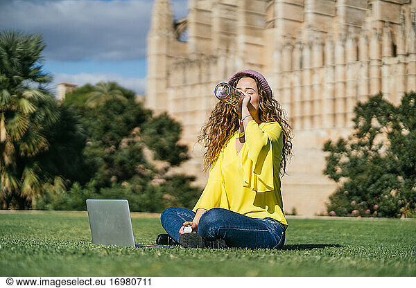 Young woman drinking water on lawn