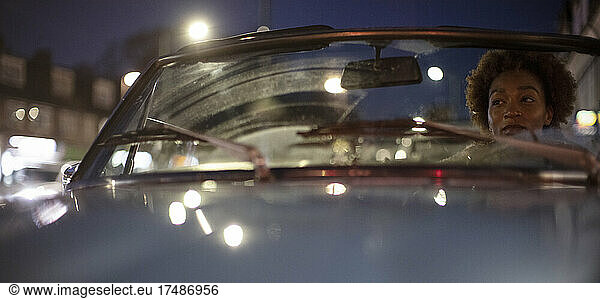 Young woman driving convertible at night