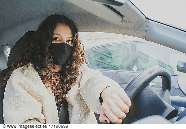 young woman driving with protective mask