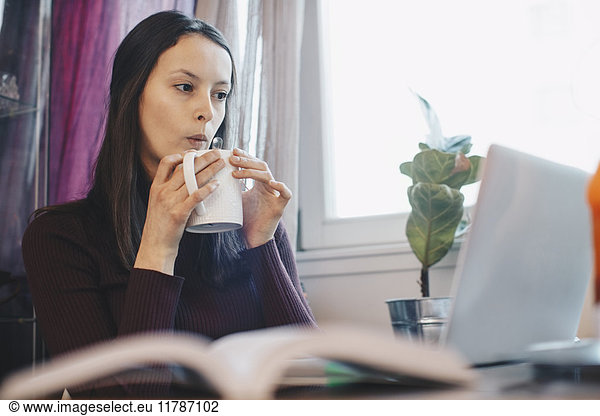 Young woman during coffee break against window in college dorm