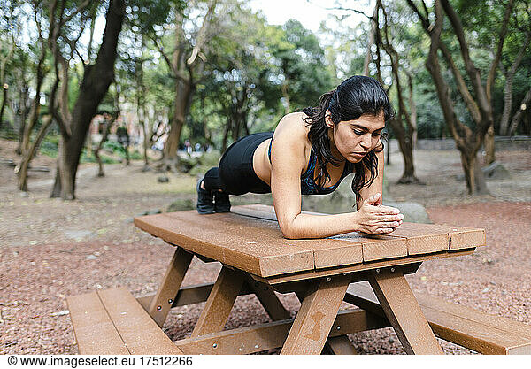 Young woman during workout outdoors  plank on table