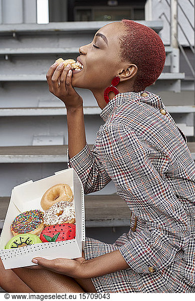 Young woman eating a doughnut from the box
