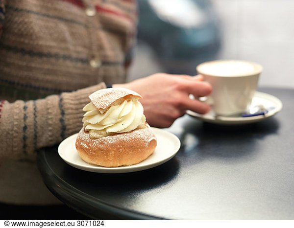 Young woman eating a piece of pastry at a café Sweden.
