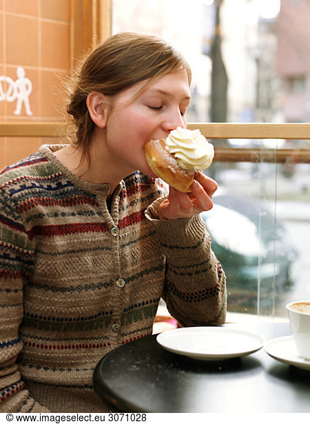 Young woman eating a piece of pastry at a café Sweden.