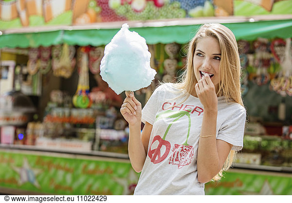 Young woman eating candy floss at a fun fair